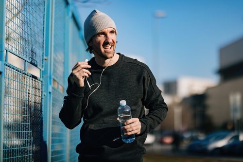 piti Happy male athlete with a bottle of water walking outdoors.