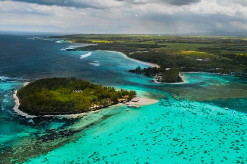 Aerial picture of the east coast of Mauritius Island. Beautiful lagoon of Mauritius Island shot from above. Boat sailing in turquoise lagoon Aerial picture of the east coast of Mauritius Island. Beautiful lagoon of Mauritius Island shot from above. Boat sailing in turquoise lagoon
